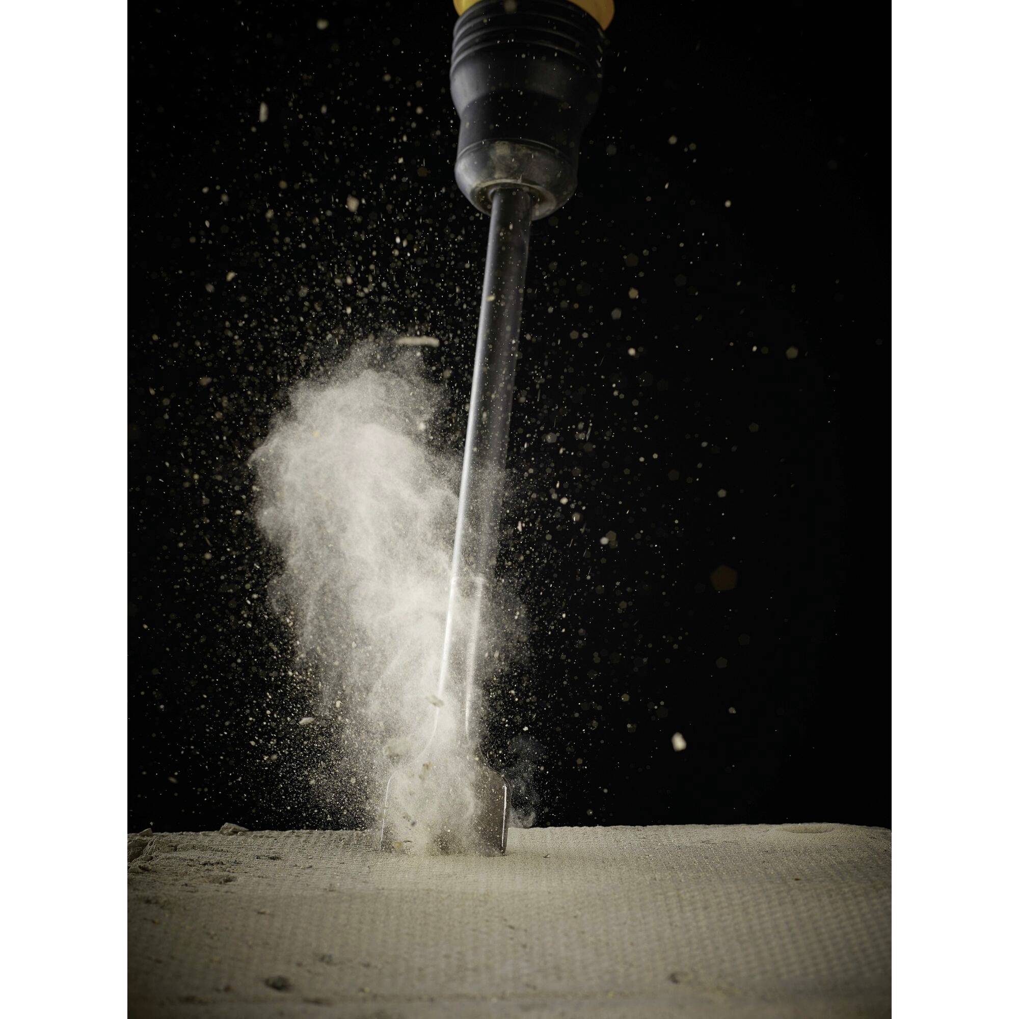 Drill pierces through concrete, creating a dust cloud; symbolises construction or renovation work.