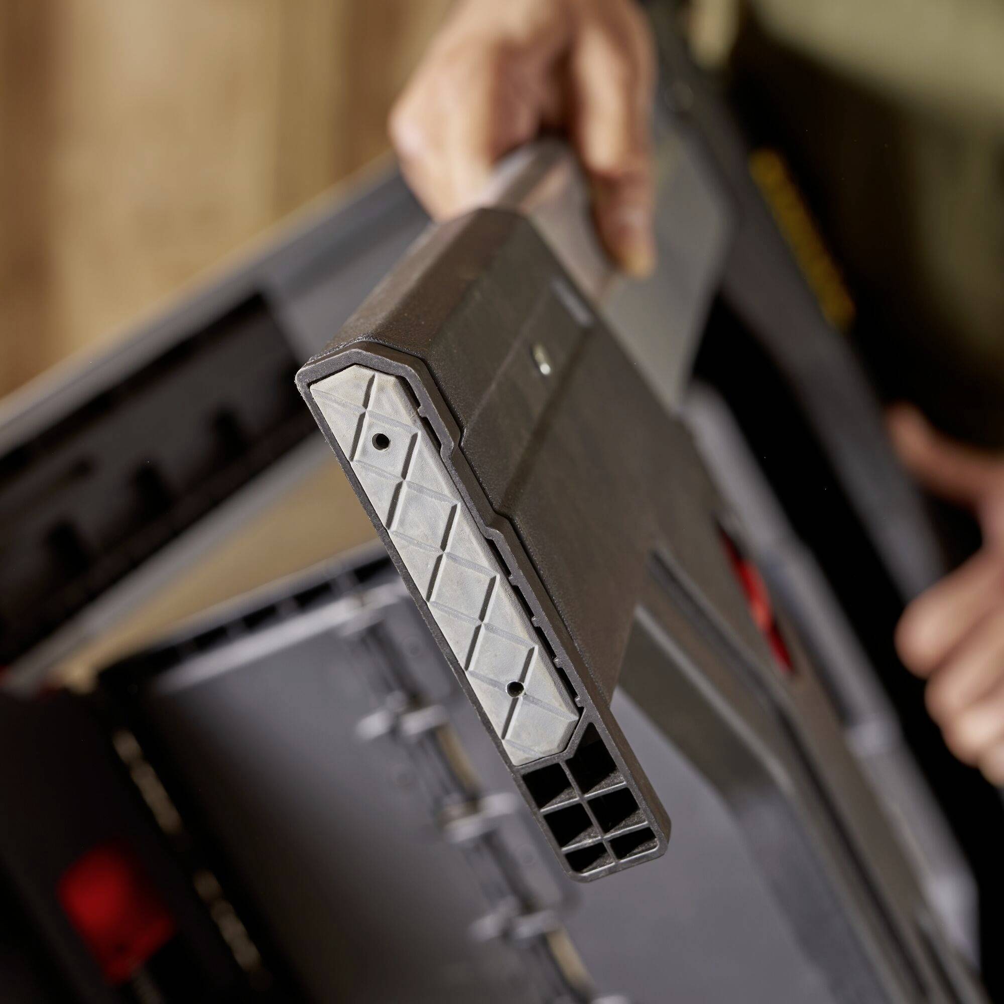 A person is inserting a battery into a charger. The focus is on the device and the hand holding the battery.