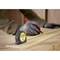 A person is measuring a wooden board with a tape measure and marking it with a red pen.