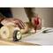 A person is drawing a line on paper with a red pencil and using a tape measure for precise measurement.