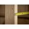 A yellow tape measure is measuring the distance between two wooden beams in a construction environment.