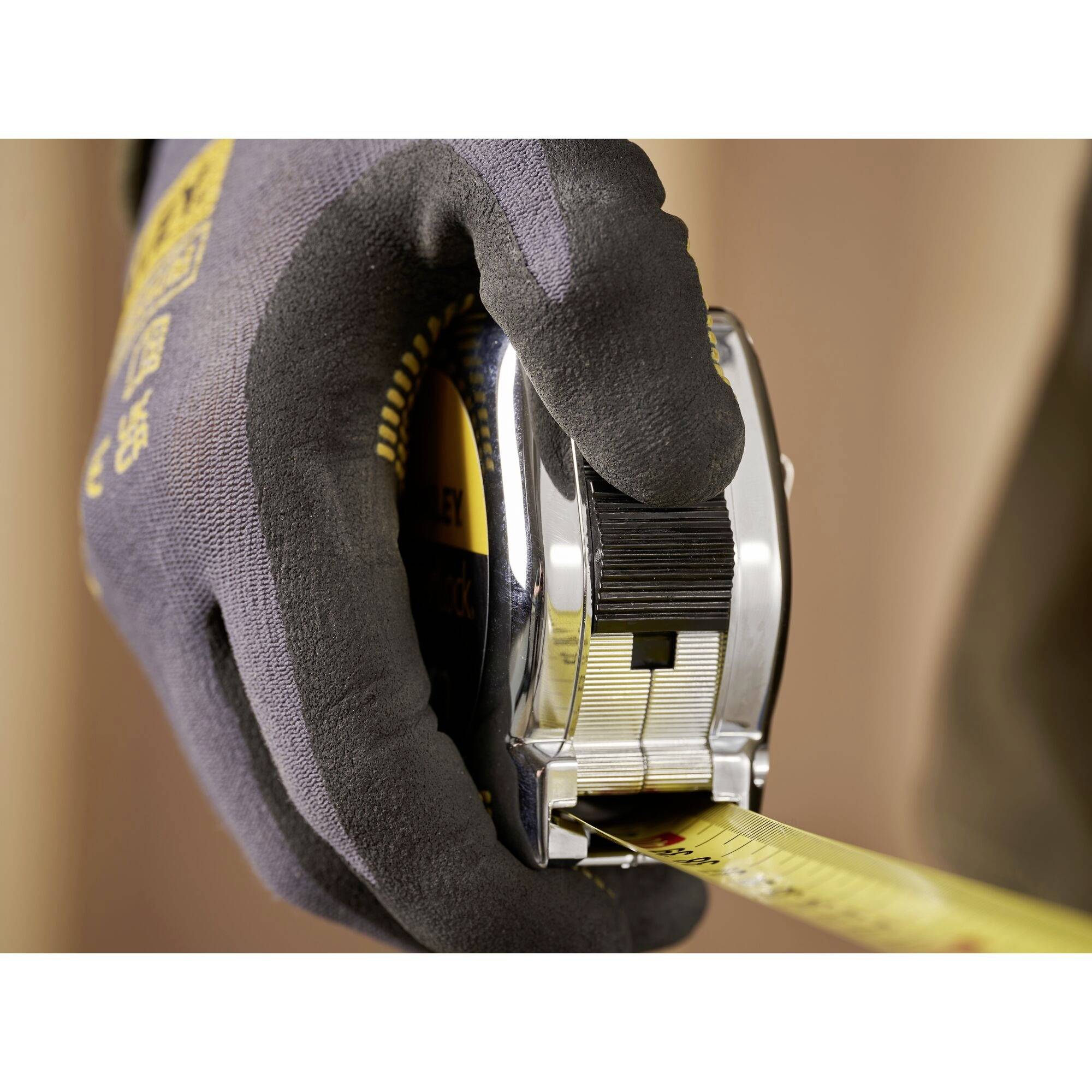 A gloved hand holds an extended tape measure.