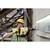 A construction worker wearing a hard hat and safety glasses is drilling into a concrete wall with a yellow drill on a building site.