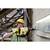 A construction worker wearing a yellow hard hat and ear protection is using an electric drill to work on a concrete wall.
