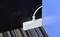 A white cable management system lies on a striped carpet, arranging a single power cable between a black and blue wall.
