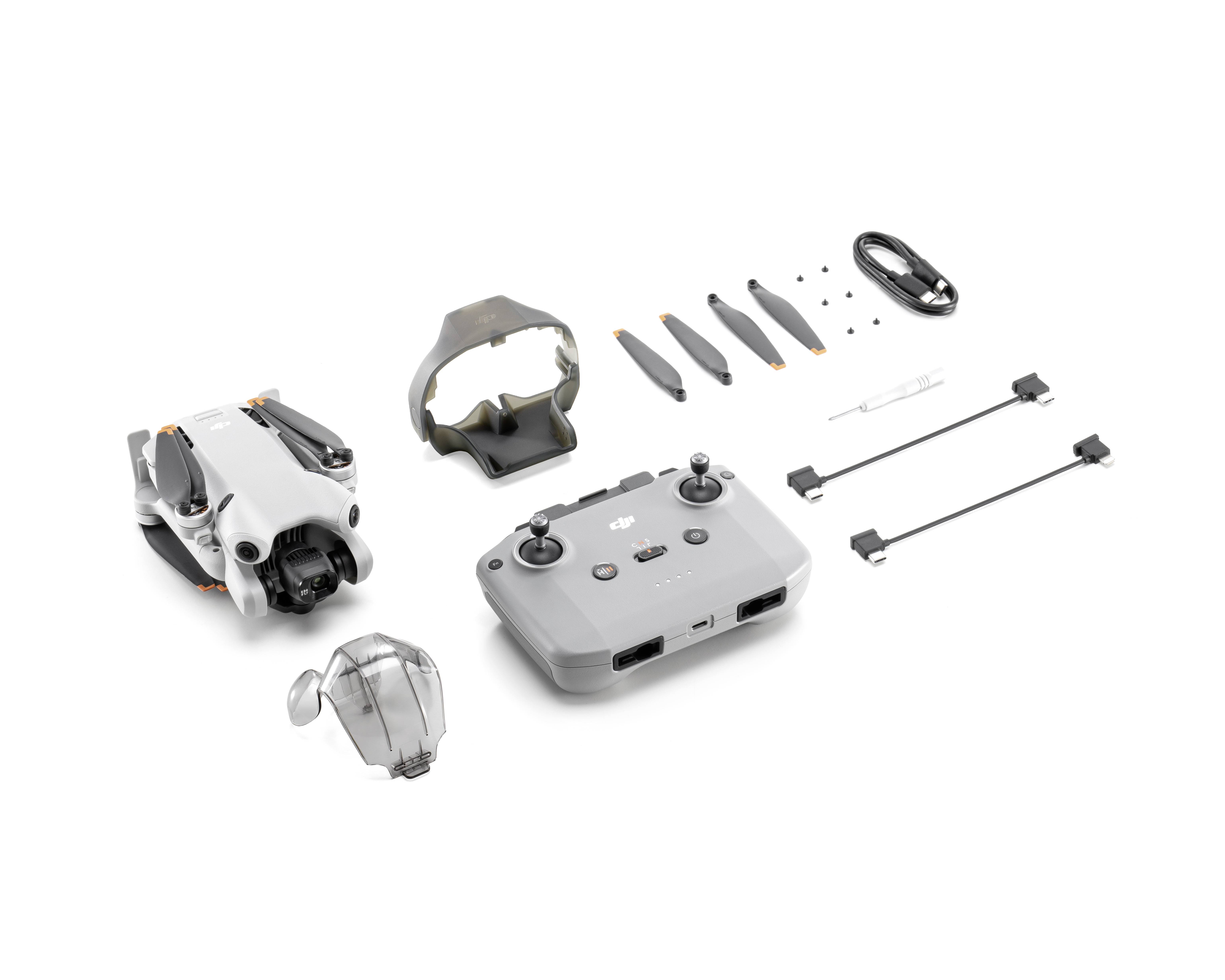 Compilation of drone components: a folded drone, remote control, propellers, cables and accessories on a white background.
