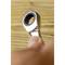 A spanner is held in a hand. The focus is on the ring spanner part. The wooden background is blurred.