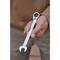 A man is holding a combination spanner in his hand, ready to tighten or loosen a screw. The spanner has an open-end and a ratchet opening.