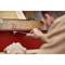 A person is tightening a screw on a large red machine using a spanner. Focus on the hand and the tool.