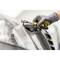 A person wearing gloves is using a screwdriver on a car, likely on a headlight, in a workshop.