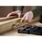 A person is using a ratchet to turn a screw into a wooden board. In the foreground, an open toolbox with various bits is laid out.