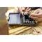 Two hands are working with a socket wrench set. One hand is holding a ratchet handle, the other a socket attachment. Tools are lying in an open box.