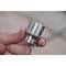 A hand holds a silver socket extension with the number '27' engraved on it, against a blurred background.