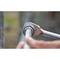 A hand is holding a spanner, tightening a nut on a metal pipe. The focus is on the tool and the connection.