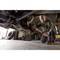 A person is working in a garage underneath a car and using a spanner to repair parts on the chassis.