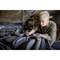 A woman with tattoos is repairing an engine in a workshop, focused on her work while holding a tool.