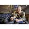 A person is working on a car part in a workshop and using a spanner. Workshop equipment is visible in the background.