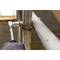 A ratchet tightens a screw on a metal construction. Background blurred with a brick wall.