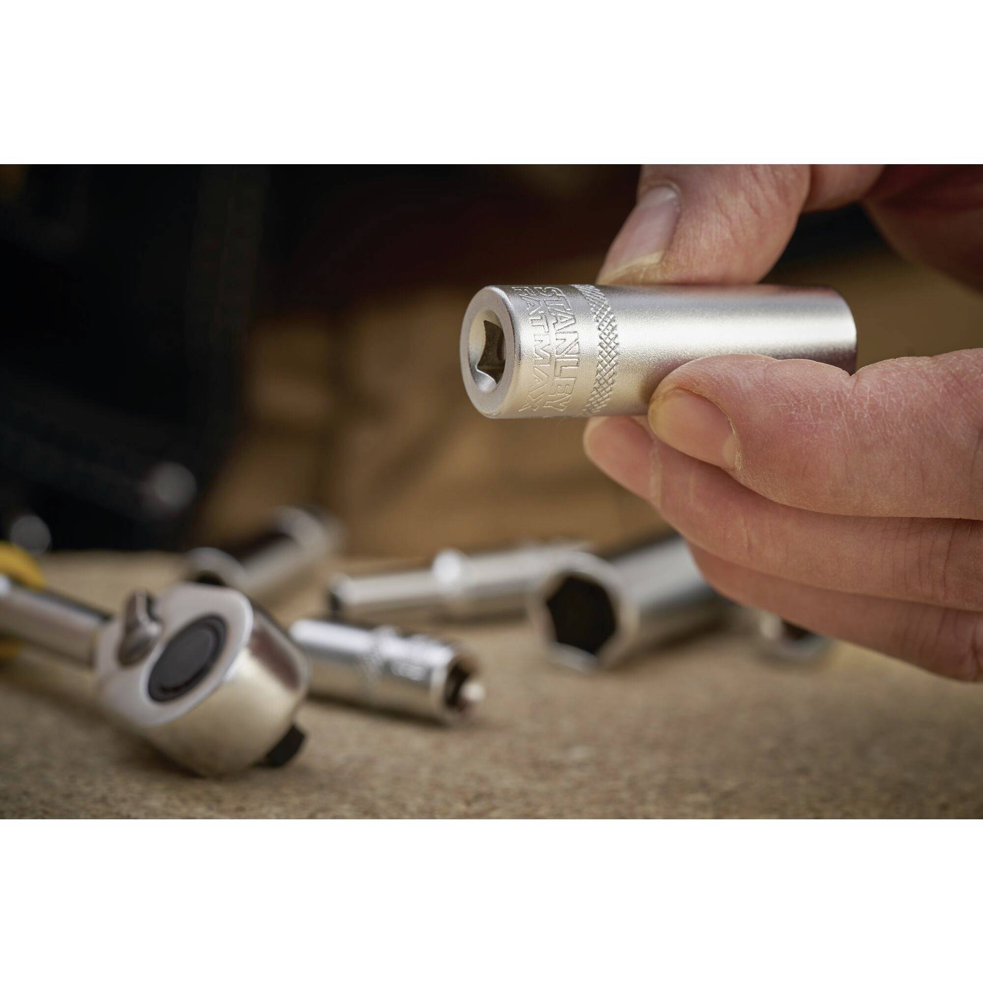 A hand holds a hex nut over a table scattered with tools, indicating repair or assembly work.