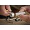 A person is using a ratchet to tighten a screw. Several metal socket attachments are lying in the background.