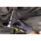 A person is working underneath a vehicle with a spanner, tightening a bolt. They are wearing dark gloves.