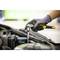 A person wearing work gloves is repairing an engine with a ratchet tool in a workshop environment.