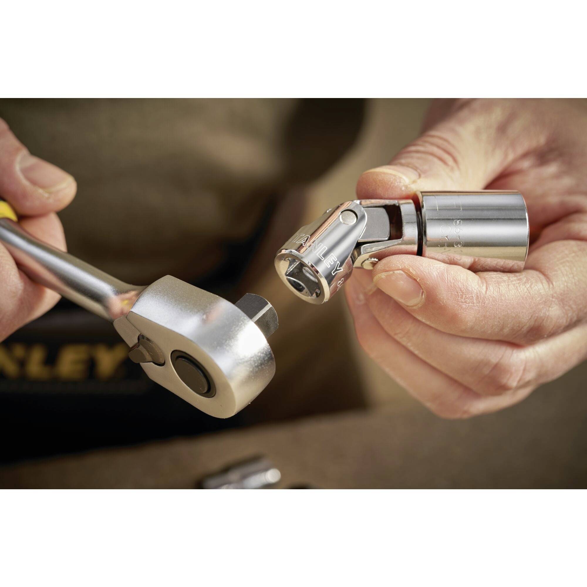 A person is attaching a socket to a ratchet, ready for use during vehicle or machinery maintenance.