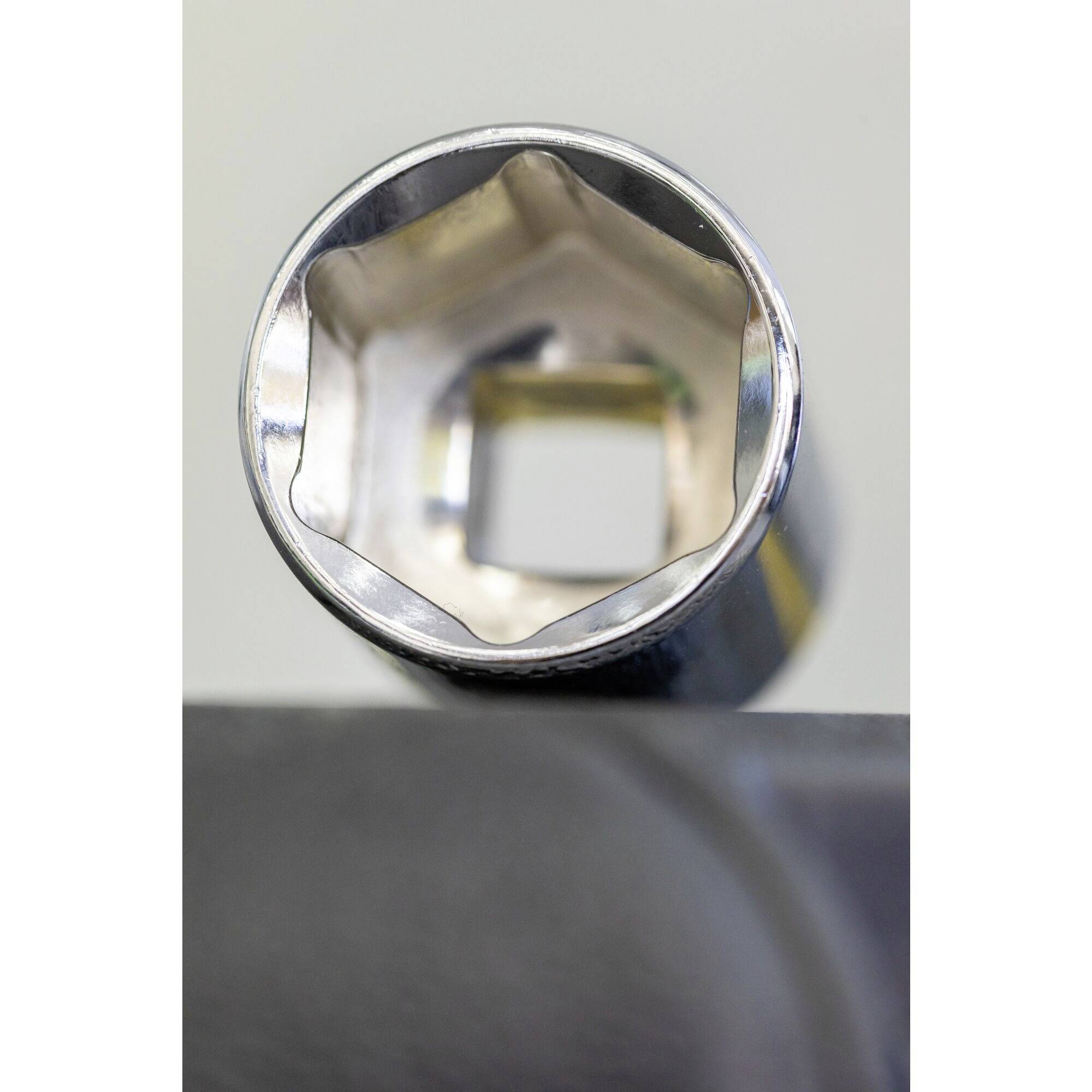 Close-up of a hexagonal socket wrench head viewed from above, resting on a dark, blurred background.