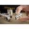 A hand is holding a silver socket attachment in front of a blurred background with tools.