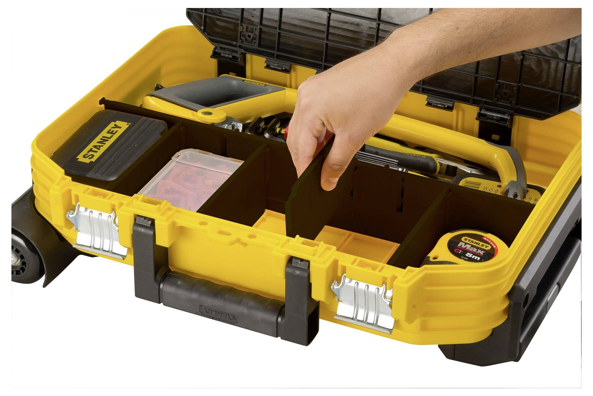 A yellow toolbox with multiple compartments, filled with various tools such as a hammer, tape measure, and screwdriver. A hand reaches towards one of the compartments.