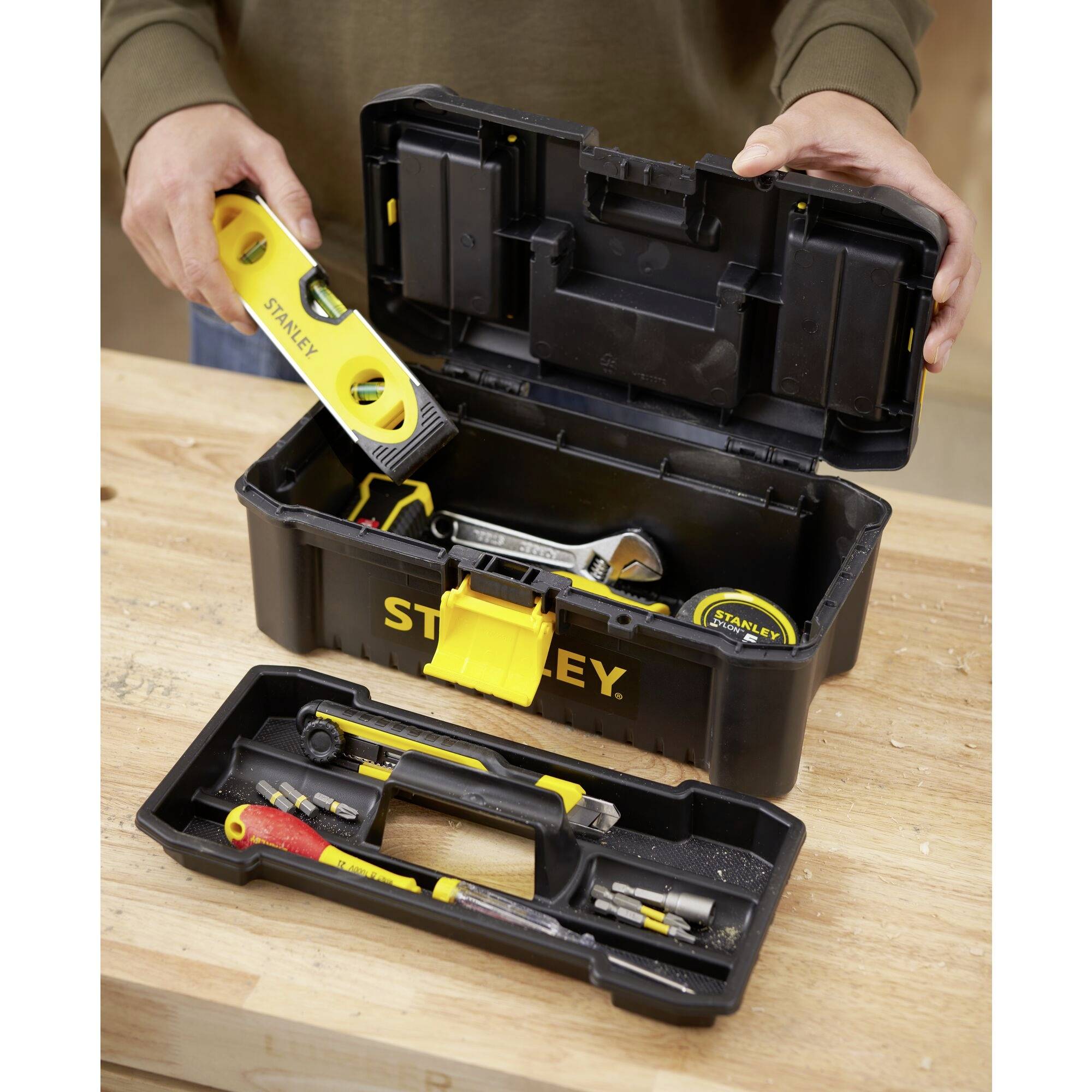 An open toolbox on a table displays various tools, including a spirit level, screwdriver and hammer.