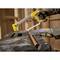 A person is cutting a copper pipe with a hacksaw on a workbench. The person is wearing gloves.