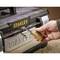 A hand opens a combination lock on a Stanley toolbox. The focus is on the security provided by the lock.