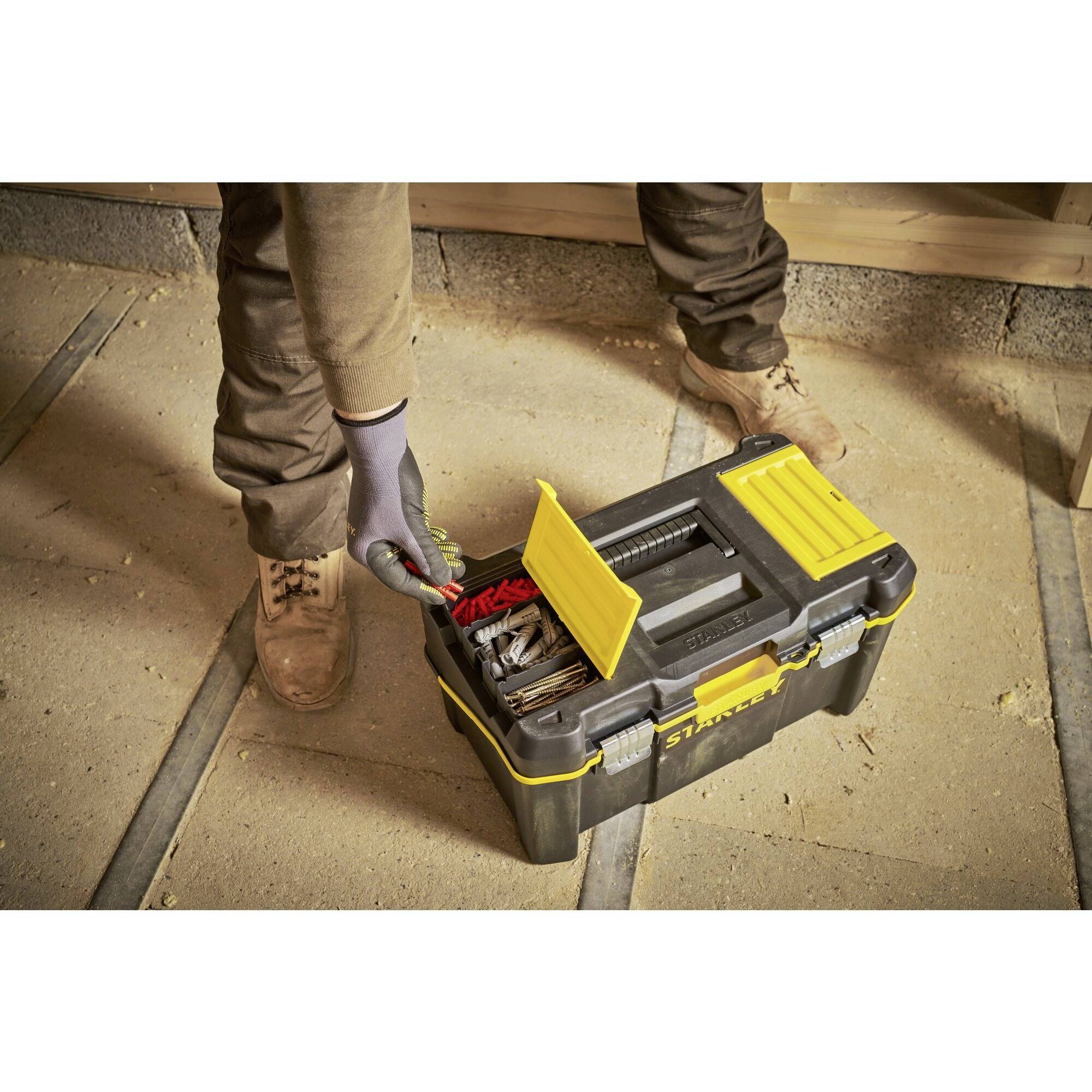A person opens a toolbox on a construction site. The box contains various tools and materials.<br><br>Note: The translation is already in British English, maintaining the original meaning and structure of the German text.