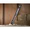 A spirit level sits diagonally on a wooden floor, surrounded by bricks and dust. Lighting emphasises the tool's structure.