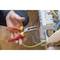 A person is holding a long needle-nose pliers and working on an electrical connection board with multiple cables.
