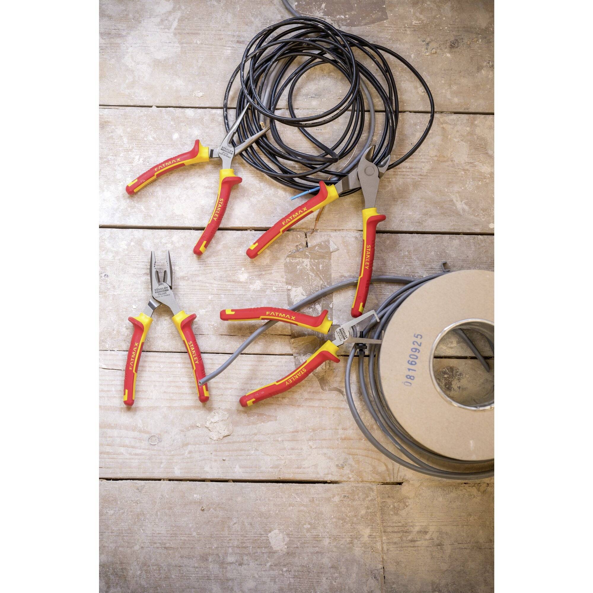 A cable reel with cables and four pliers on a wooden floor.