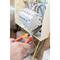 A person is using pliers to work on wires in an electrical fuse box. The box is open and shows several wires.