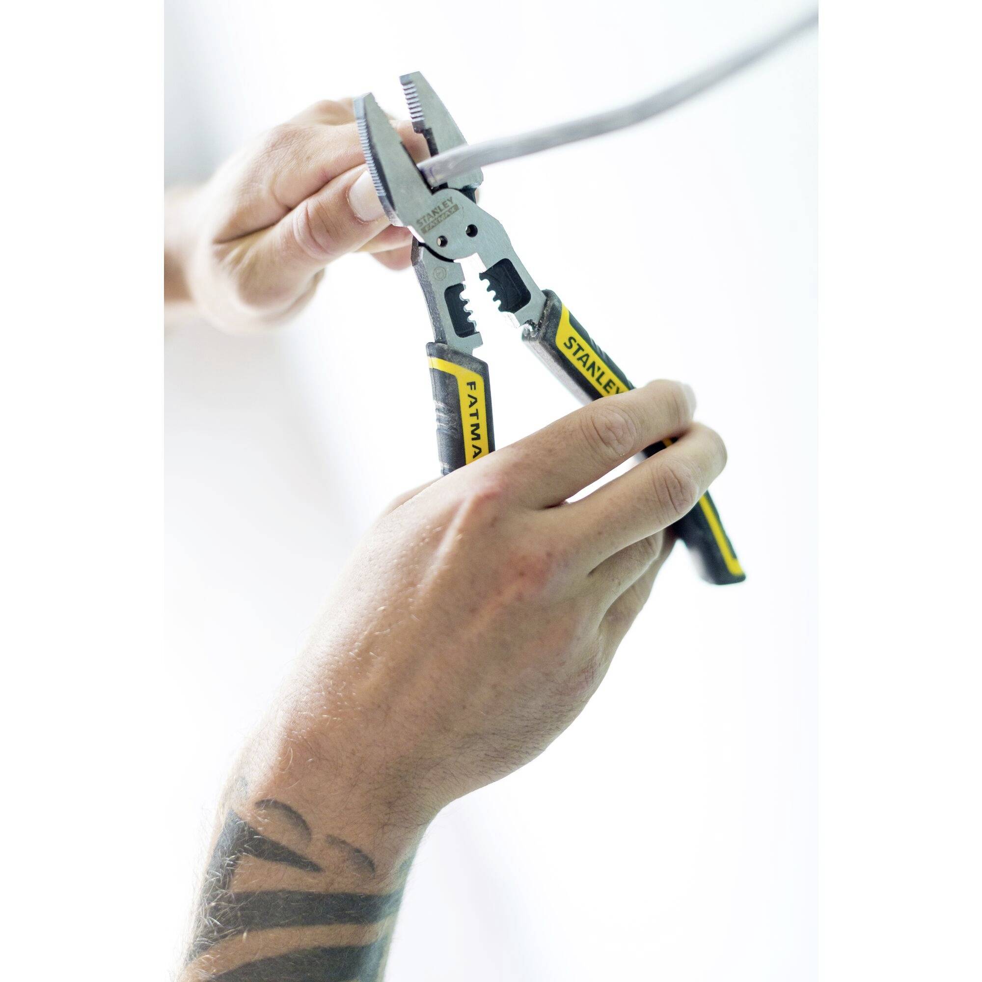 Two hands are holding a combination pliers and cutting a cable.