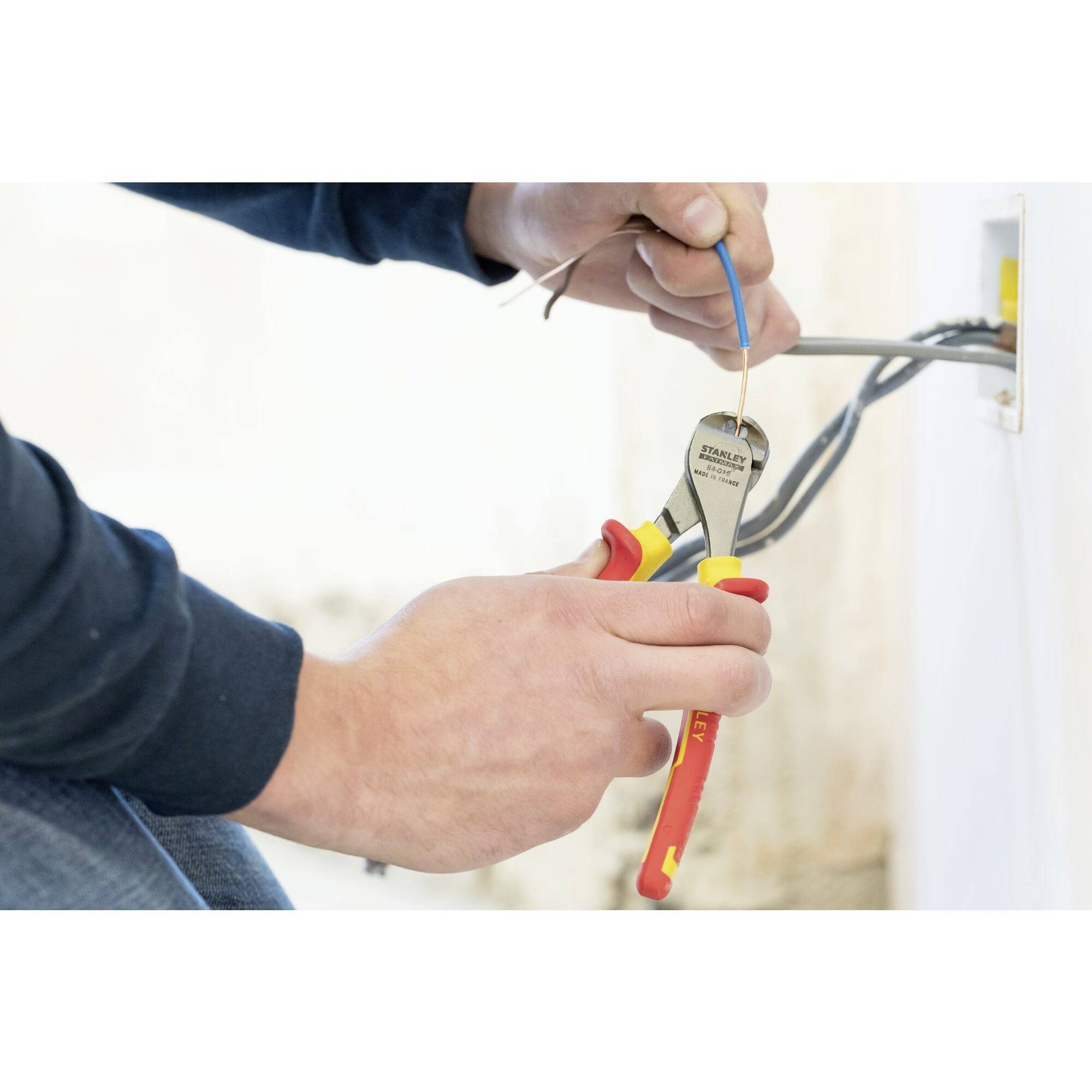 A person is working on a socket, holding a cable and using pliers to handle electrical wires.