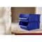 Two blue plastic crates stacked on top of each other are standing on a wooden floor next to a white balustrade.
