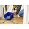 A person is kneeling on the wooden floor and using a yellow cordless drill. A blue box of screws is beside them.