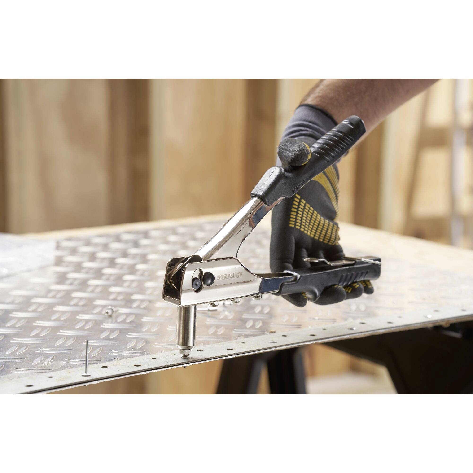 A person is using a pair of pliers to work on a metal sheet, with a focus on craftsmanship and tool usage.