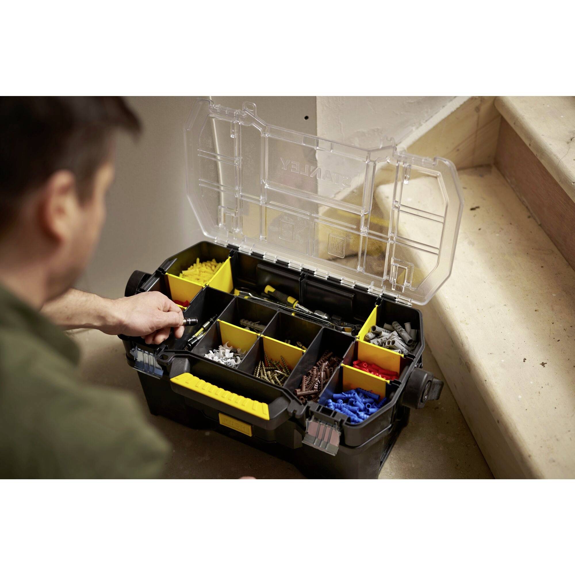 A person opens a toolbox with various compartments containing different screws and wall plugs.