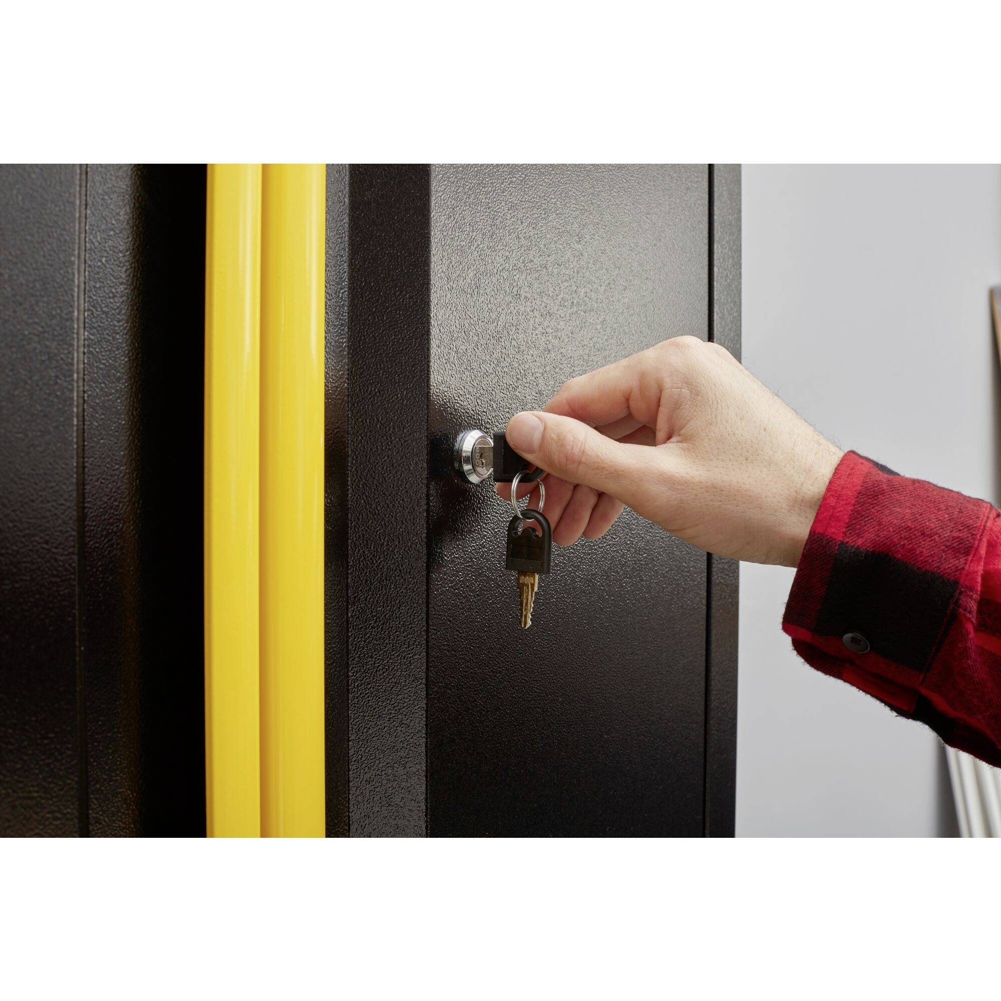 A hand unlocks a black cabinet with a key. Yellow cables are visible next to the lock.