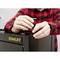 A person in a red and black checked shirt is assembling a black Stanley tool cabinet. They are using a small metal tool.