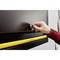 A hand turns a key in a lock on a black drawer with a yellow handle. The person is wearing a red and black checked shirt.
