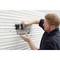 A man is attaching a black basket to a white, ribbed panel.