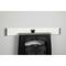 A black folding stool stands in front of a white, horizontal measuring stick on the wall.