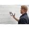 A man is installing a black hook onto a ribbed, white professional wall rail system.